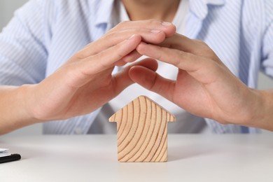 Photo of Real estate insurance. Man with wooden house figure at light table, closeup