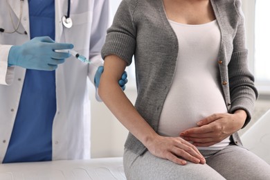 Photo of Doctor giving injection to pregnant woman at hospital, closeup