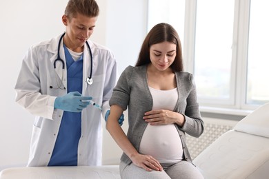 Doctor giving injection to pregnant woman at hospital