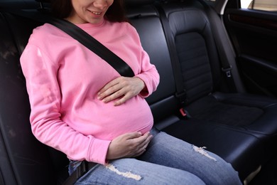 Smiling pregnant woman with safety belt in car, closeup