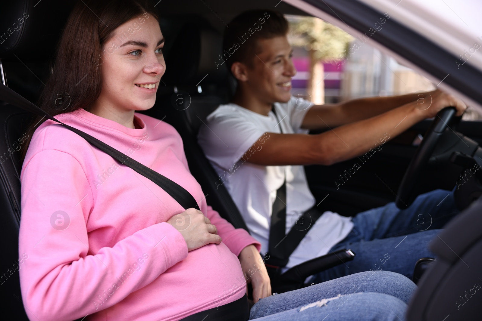 Photo of Smiling pregnant woman travelling with her husband by car