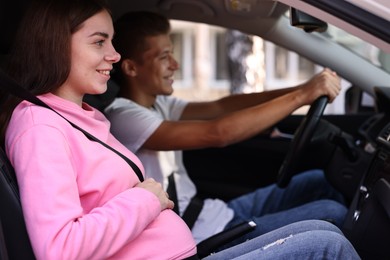 Photo of Smiling pregnant woman travelling with her husband by car