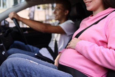 Smiling pregnant woman travelling with her husband by car, closeup