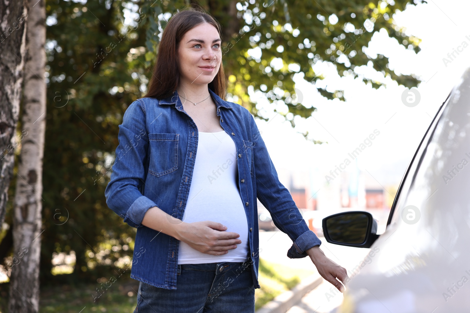 Photo of Beautiful pregnant woman opening car door outdoors