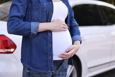 Pregnant woman near car outdoors, closeup view