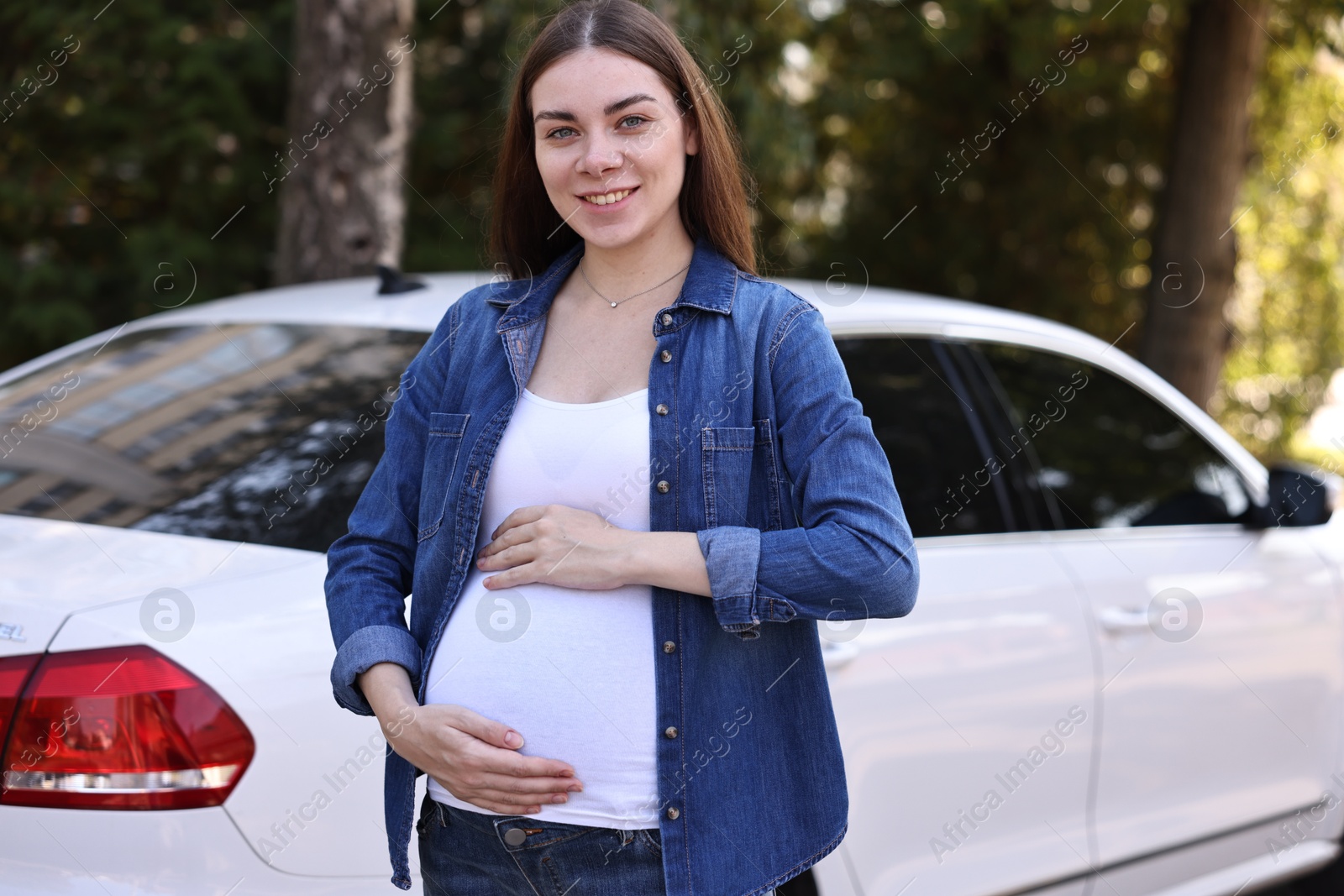 Photo of Portrait of smiling pregnant woman near car outdoors