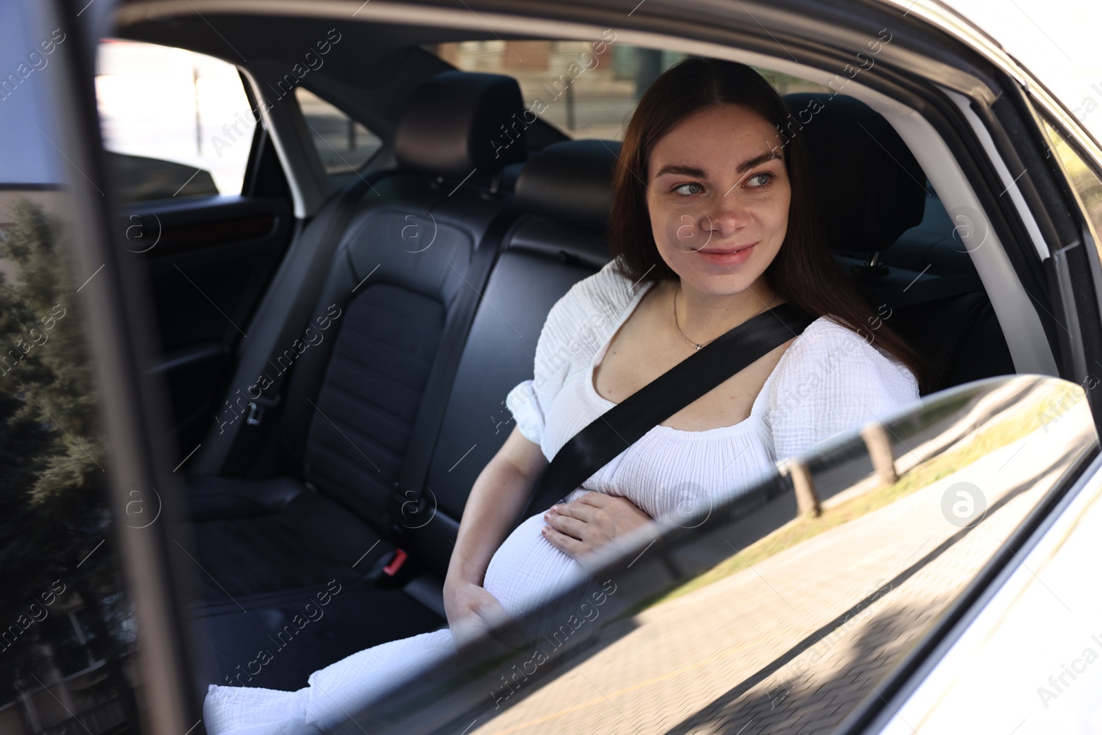 Photo of Pregnant woman with safety belt in car, view from outside