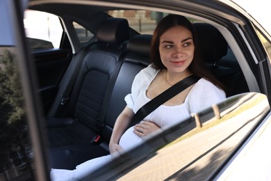 Pregnant woman with safety belt in car, view from outside