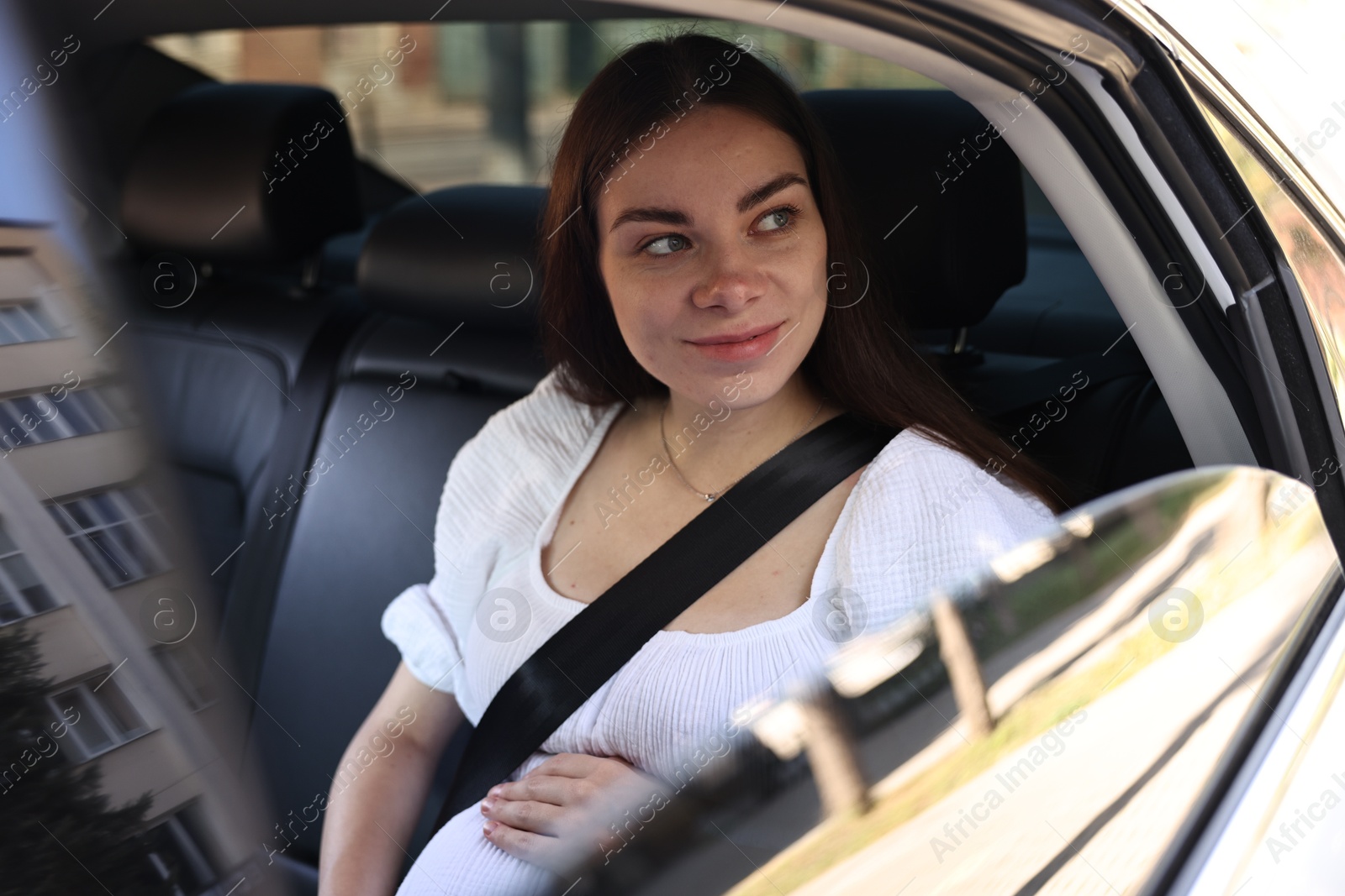 Photo of Pregnant woman with safety belt in car, view from outside