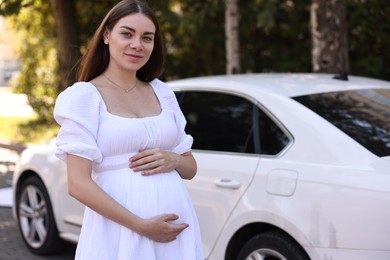 Portrait of beautiful pregnant woman near car outdoors