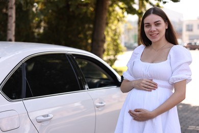 Photo of Portrait of smiling pregnant woman near car outdoors