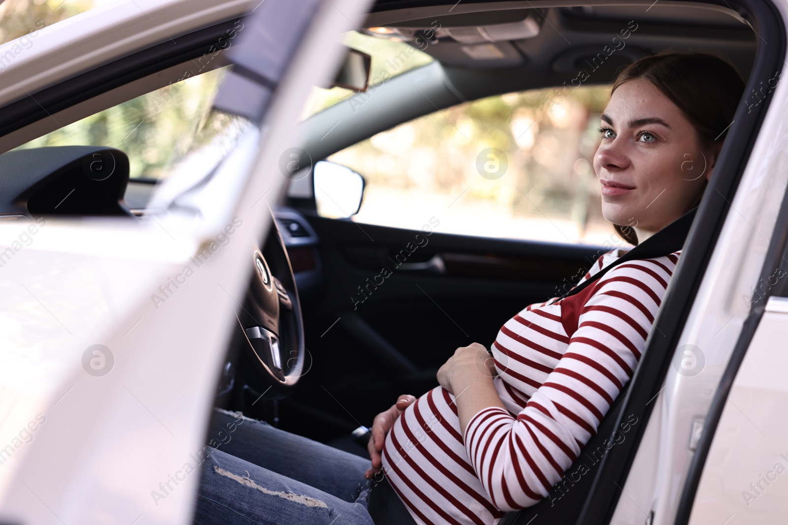 Photo of Pregnant woman with safety belt driving car, view from outside