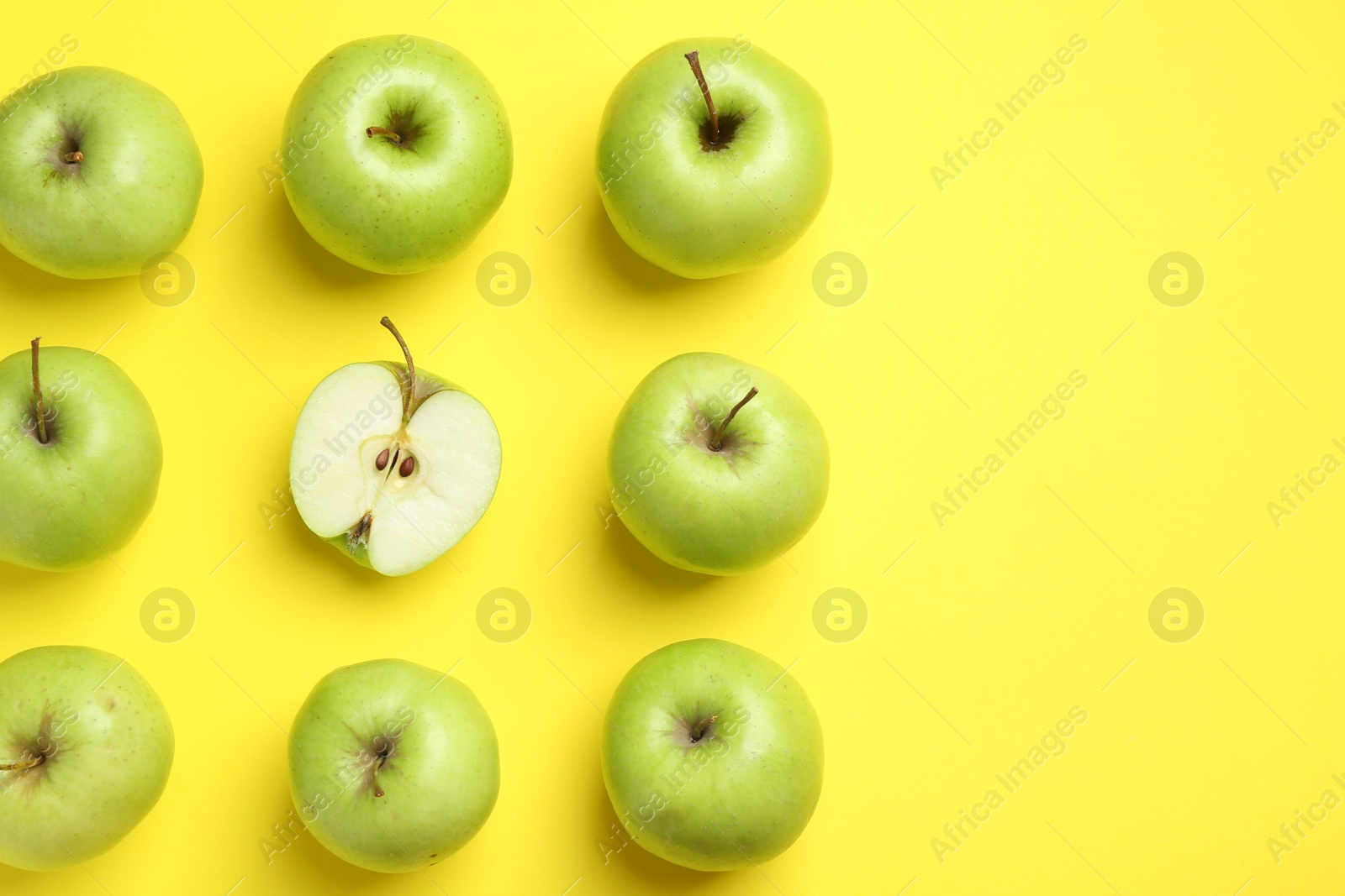 Photo of Flat lay composition with half of apple surrounded by ones on yellow background. Space for text