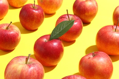 Photo of Many red apples on yellow background, closeup