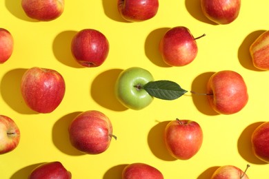 Photo of Flat lay composition with green apple surrounded by red ones on yellow background