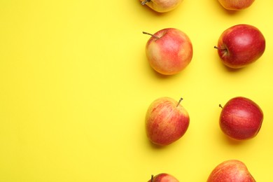 Many red apples on yellow background, flat lay. Space for text