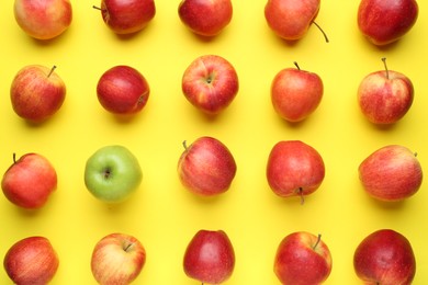 Photo of Flat lay composition with green apple surrounded by red ones on yellow background