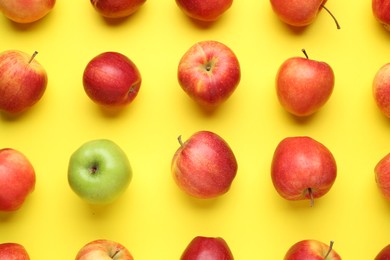 Photo of Flat lay composition with green apple surrounded by red ones on yellow background