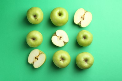 Flat lay composition with whole and cut apples on green background