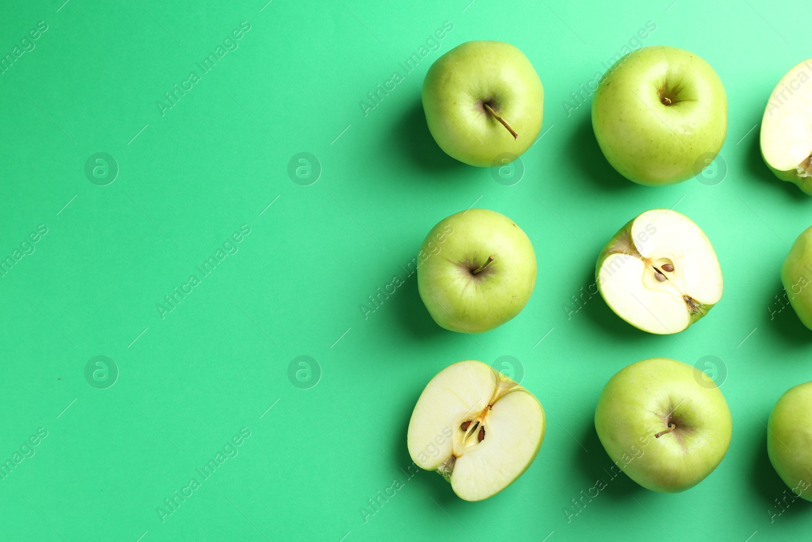 Photo of Flat lay composition with whole and cut apples on green background. Space for text