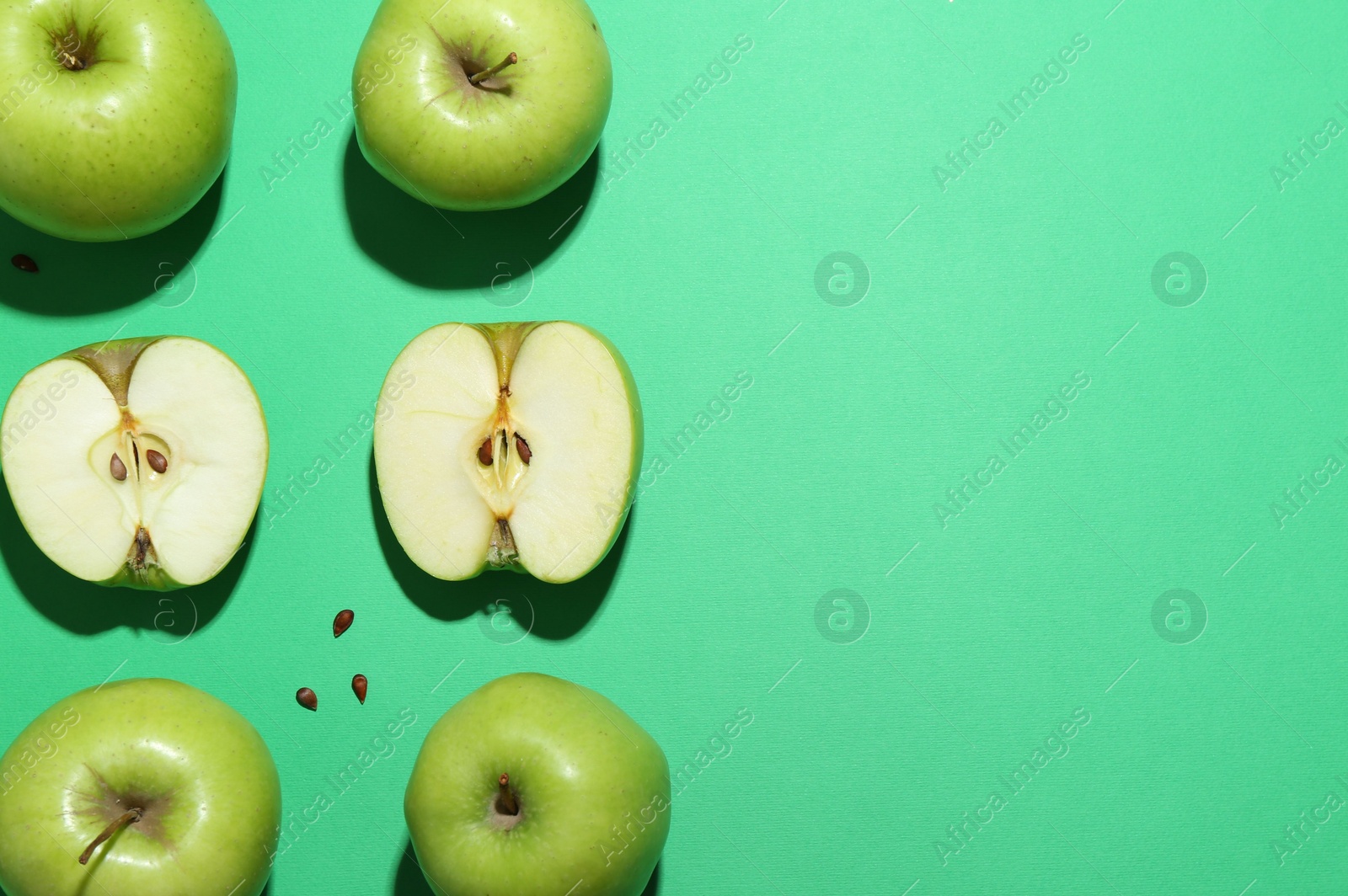 Photo of Flat lay composition with whole, cut apples and seeds on green background. Space for text