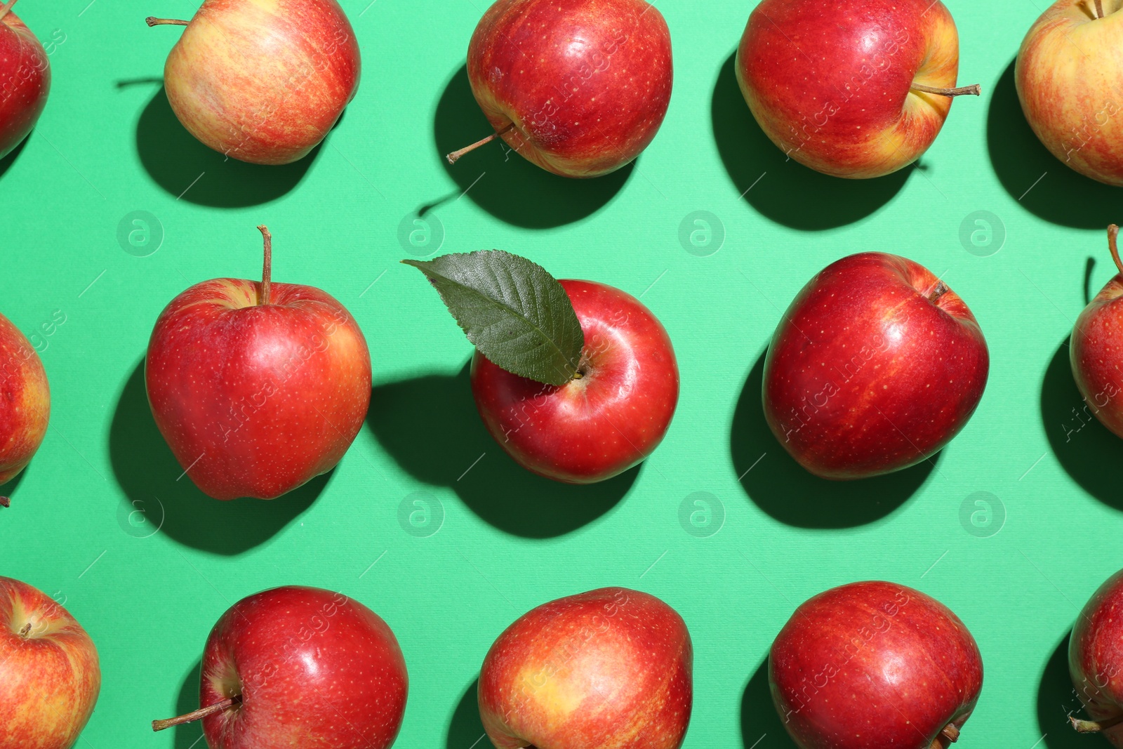 Photo of Red apples on green background, flat lay