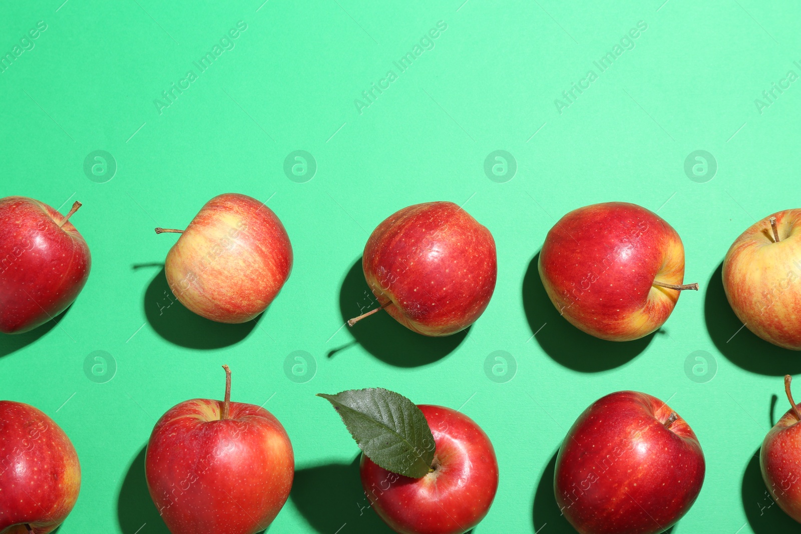 Photo of Red apples on green background, flat lay