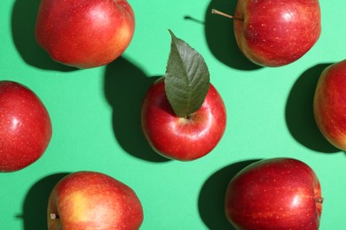 Photo of Red apples on green background, flat lay