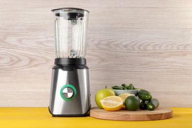 Photo of Modern blender with ingredients for smoothie on yellow wooden table. Space for text