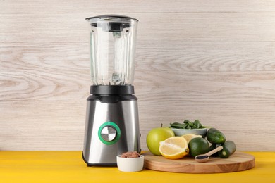 Photo of Modern blender with ingredients for smoothie on yellow wooden table. Space for text