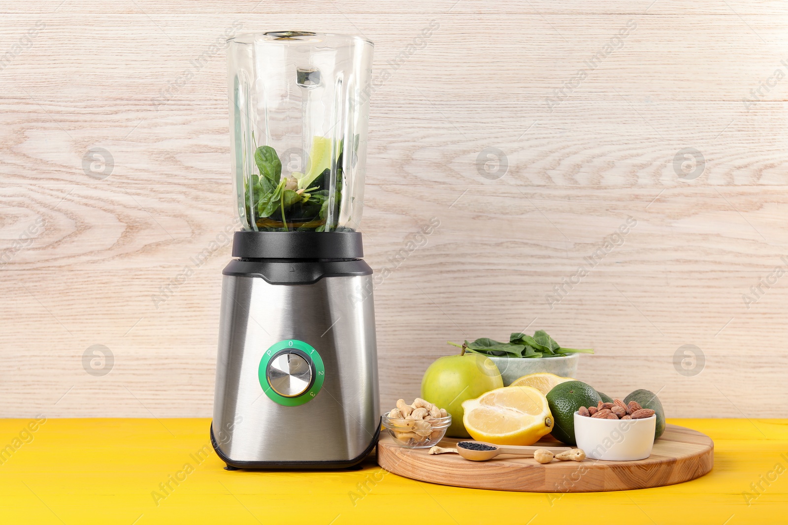 Photo of Modern blender with ingredients for smoothie on yellow wooden table