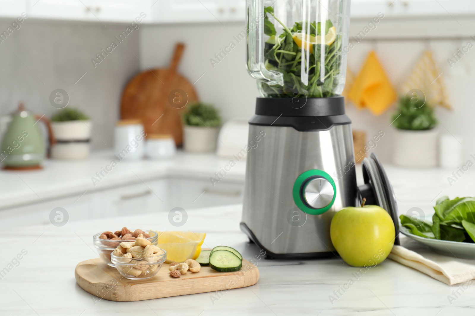 Photo of Modern blender with ingredients for smoothie on white marble table in kitchen