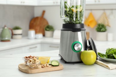 Photo of Modern blender with ingredients for smoothie on white marble table in kitchen