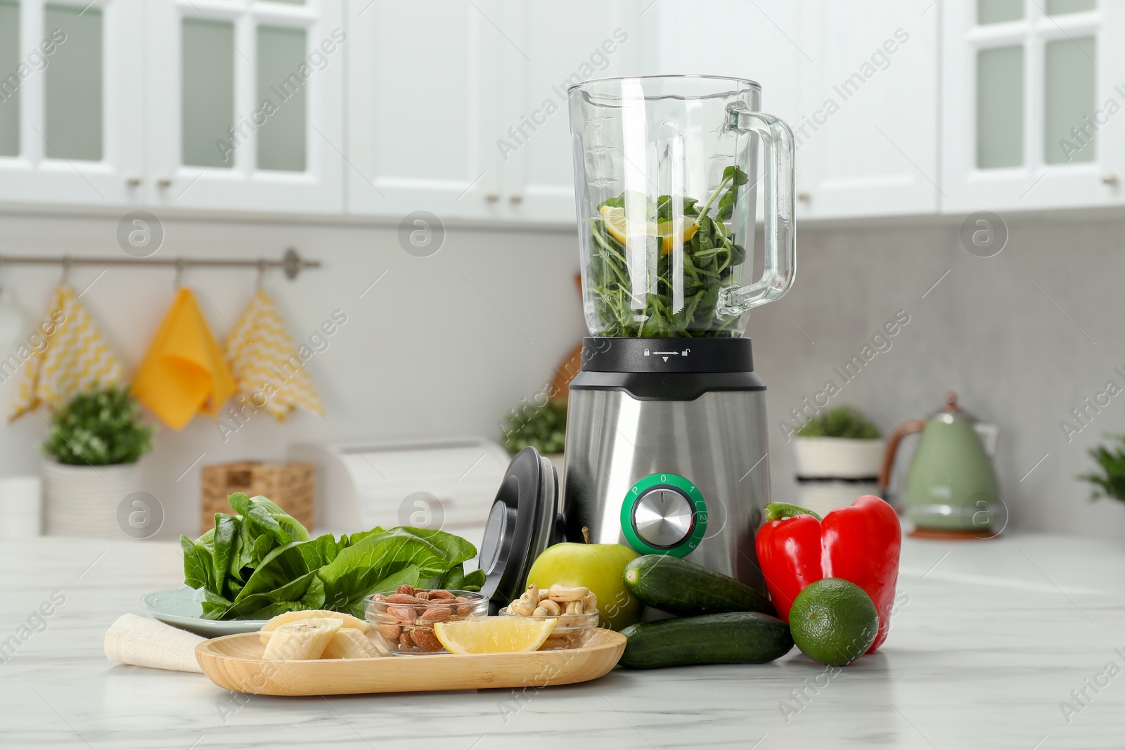 Photo of Modern blender with ingredients for smoothie on white marble table in kitchen