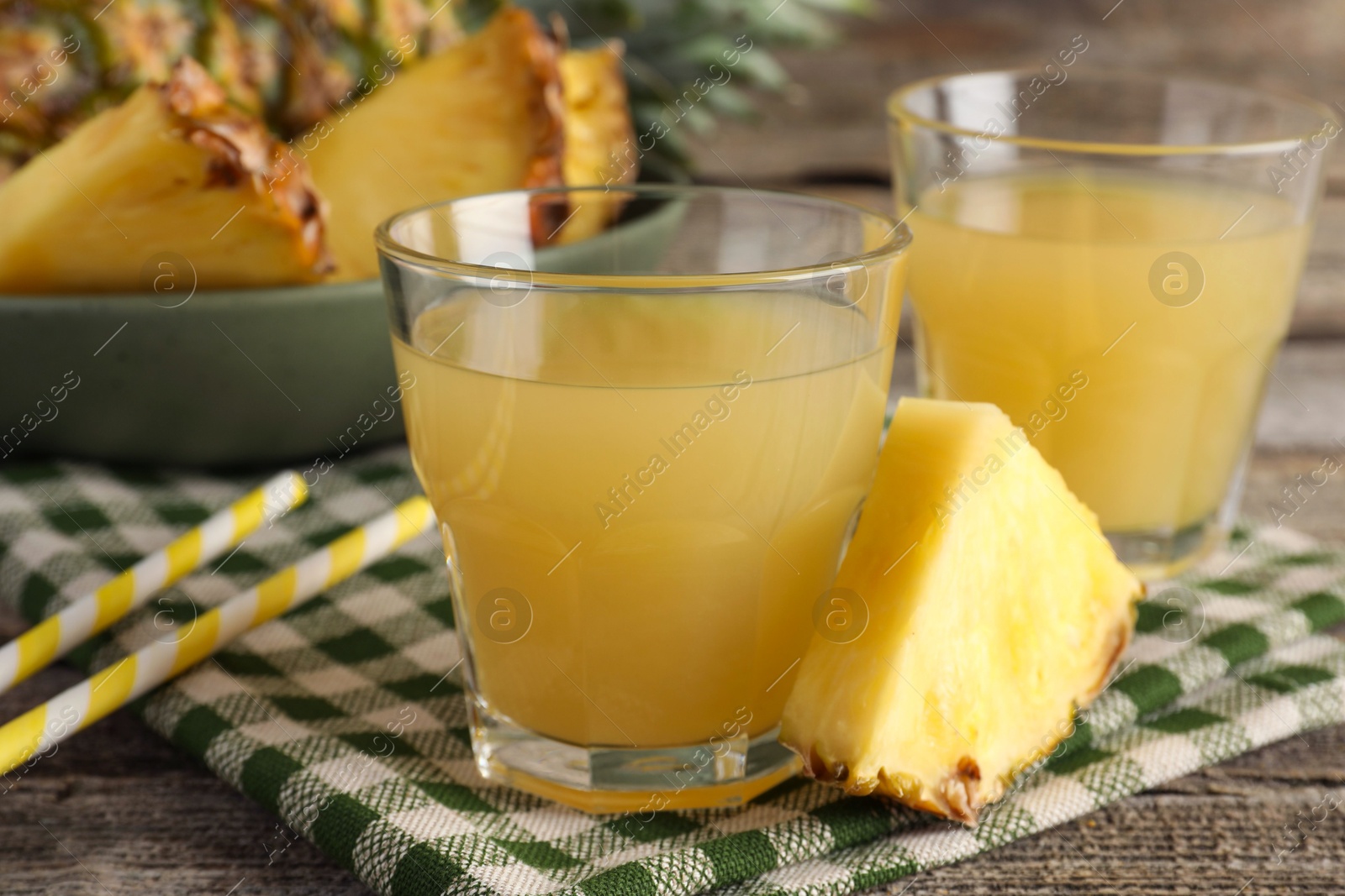 Photo of Tasty pineapple juice in glasses and slice of fresh fruit on wooden table, closeup