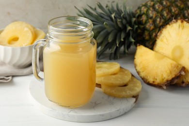 Photo of Tasty pineapple juice in mason jar and fresh fruits on white wooden table against grey background, closeup