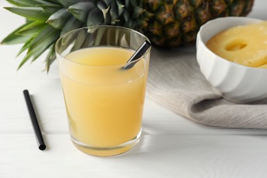 Photo of Tasty pineapple juice in glass and fresh fruit on white wooden table, closeup