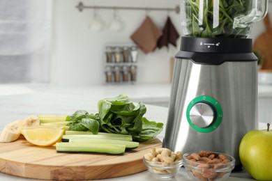 Modern blender with smoothie and ingredients on white table in kitchen