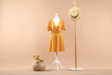 Photo of Mannequin with stylish dress, shoes and hat on beige background