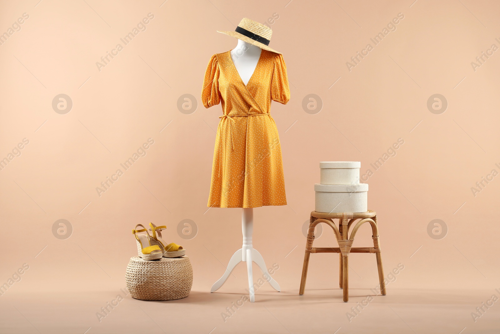 Photo of Mannequin with stylish dress, shoes and hat on beige background