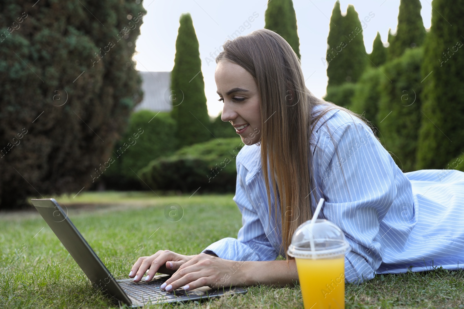 Photo of Woman using laptop on green lawn in park