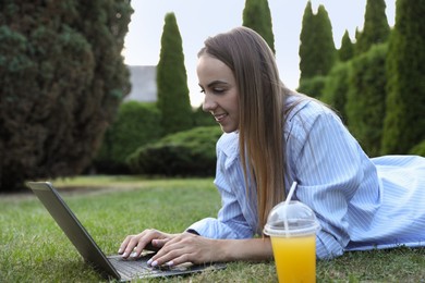 Woman using laptop on green lawn in park