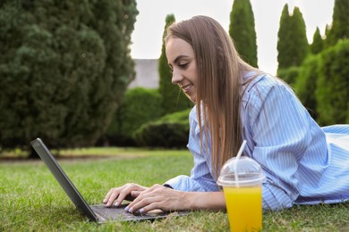 Photo of Woman using laptop on green lawn in park