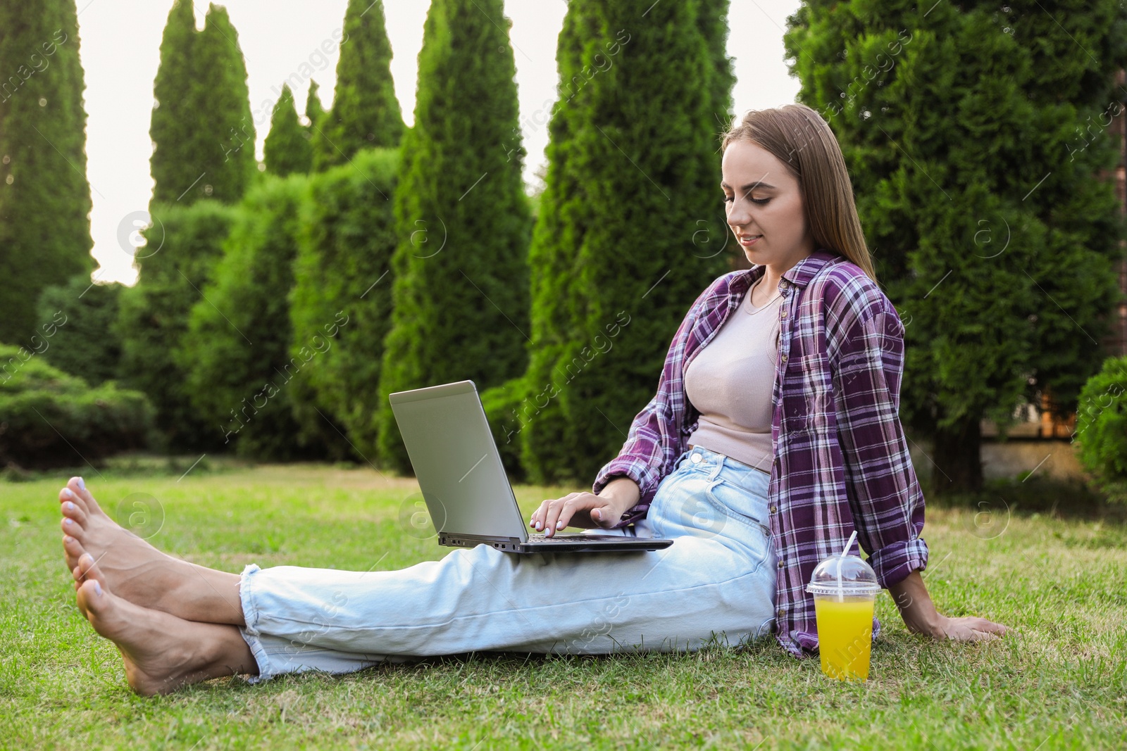 Photo of Woman using laptop on green lawn in park