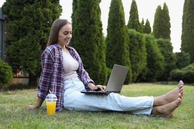 Woman using laptop on green lawn in park