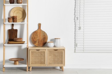 Storage stand and cabinet with kitchenware near white wall indoors