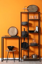 Storage stands with kitchenware near orange wall indoors