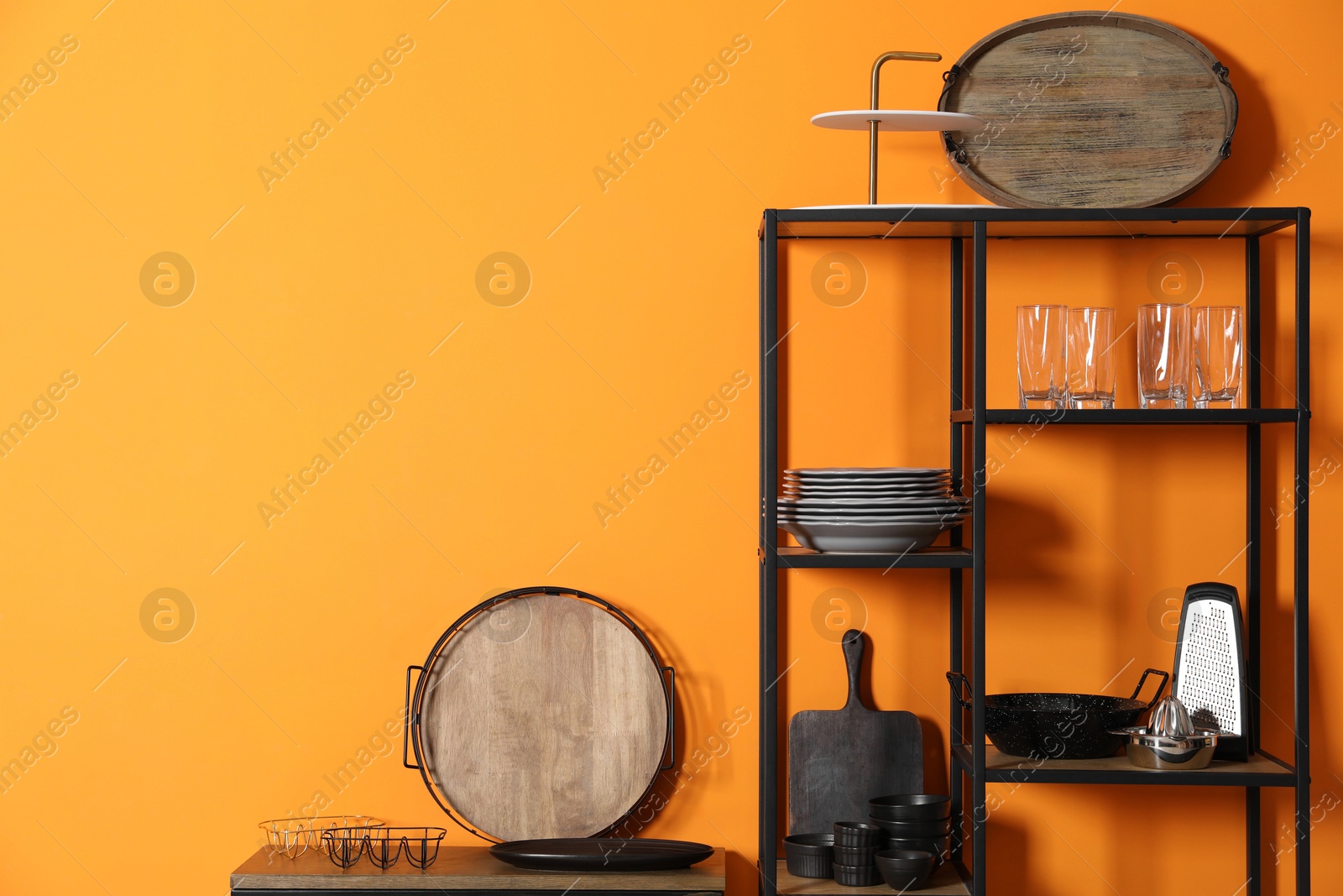 Photo of Storage stands with kitchenware near orange wall indoors