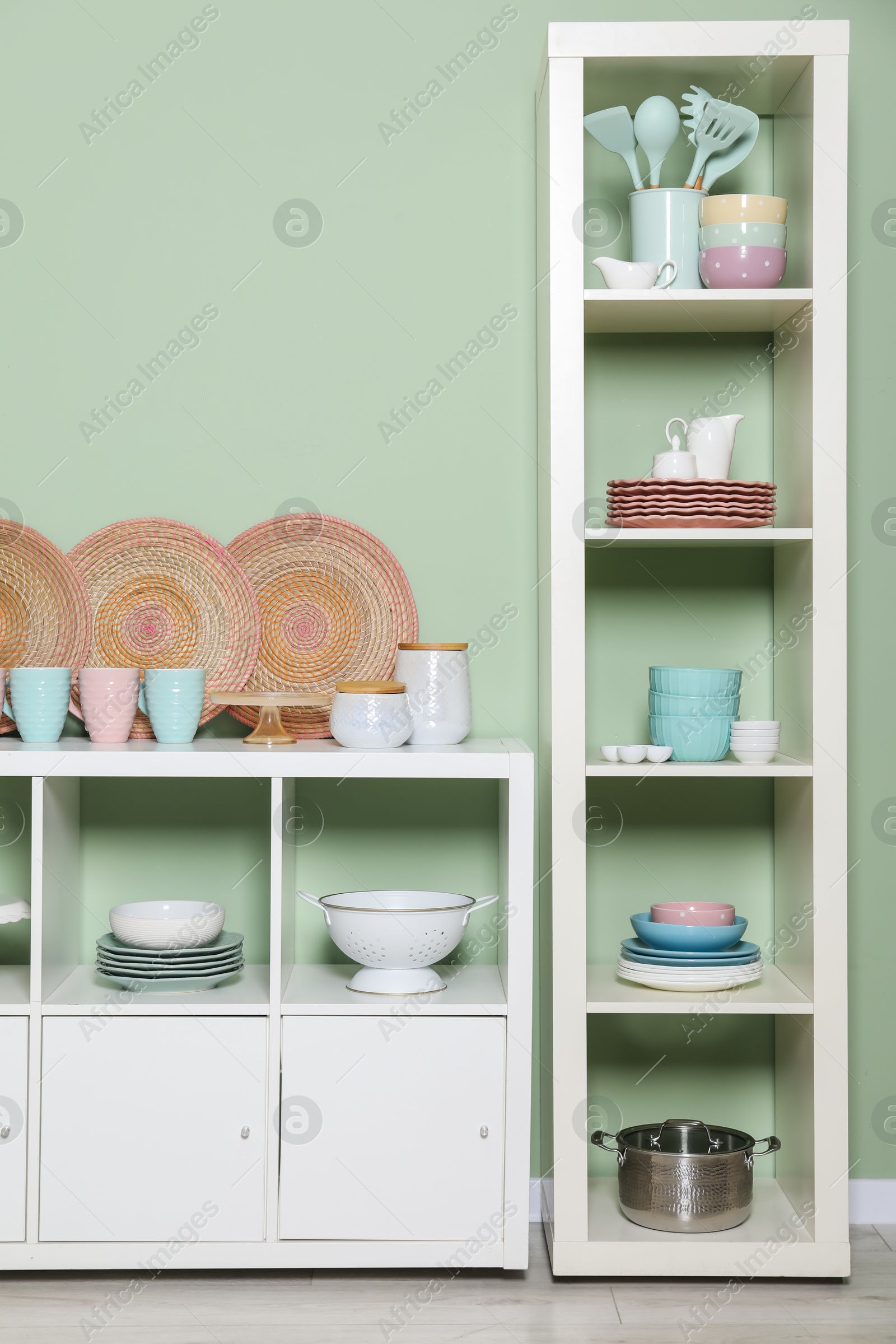 Photo of Shelving unit and storage cabinet with kitchenware near green wall