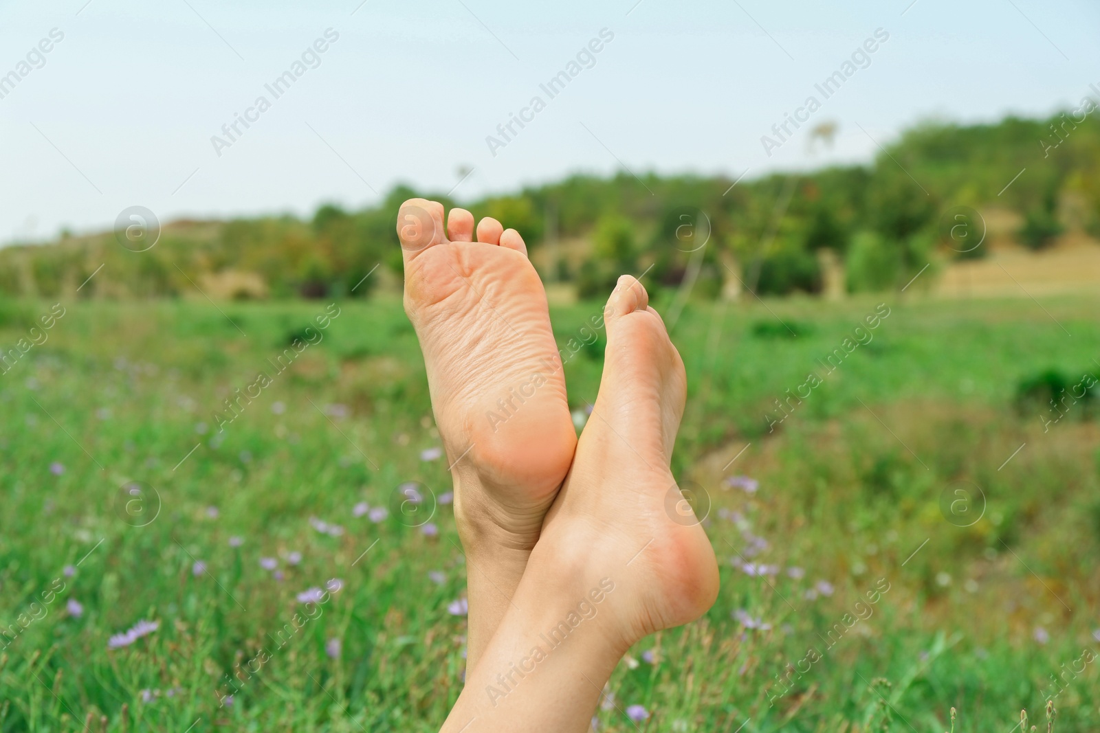 Photo of Woman lying barefoot on green grass outdoors, closeup